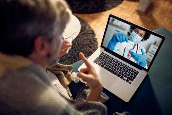 Senior man in telehealth consultation, sharing digital health data for remote review.