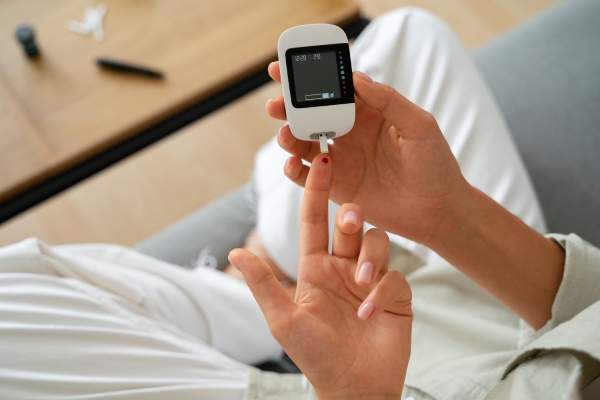 A diabetic woman checking her blood sugar levels at home using a glucose monitor.