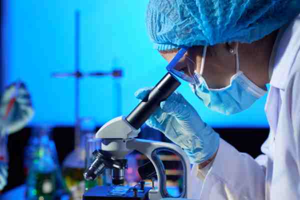 A scientist conducting diabetes-related biomedical research using a microscope.