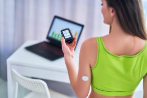 A woman with diabetes using a sensor to check glucose, highlighting the need to monitor blood sugar around exercise.
