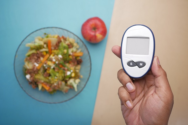 Glucometer and healthy foods on a table represent healthy eating planning for diabetes.