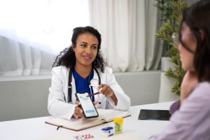 The family physician reviews the blood sugar monitoring app with the patient who has diabetes.