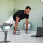 A man working out with dumbbells at home while watching a fitness video, symbolizing how exercise supports blood sugar management.