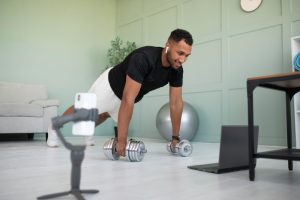 A man working out with dumbbells at home while watching a fitness video, symbolizing how exercise supports blood sugar management.