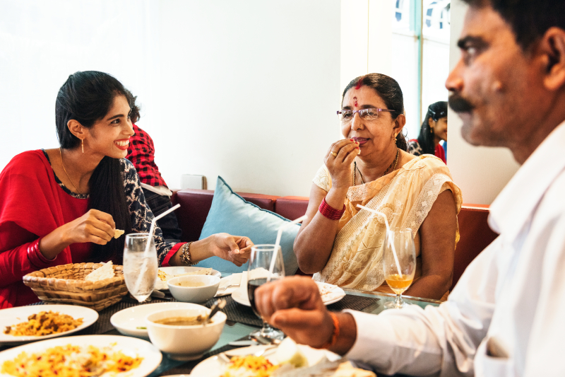 A family at a restaurant confidently ordering Indian food, selecting low glycemic index options to manage diabetes.