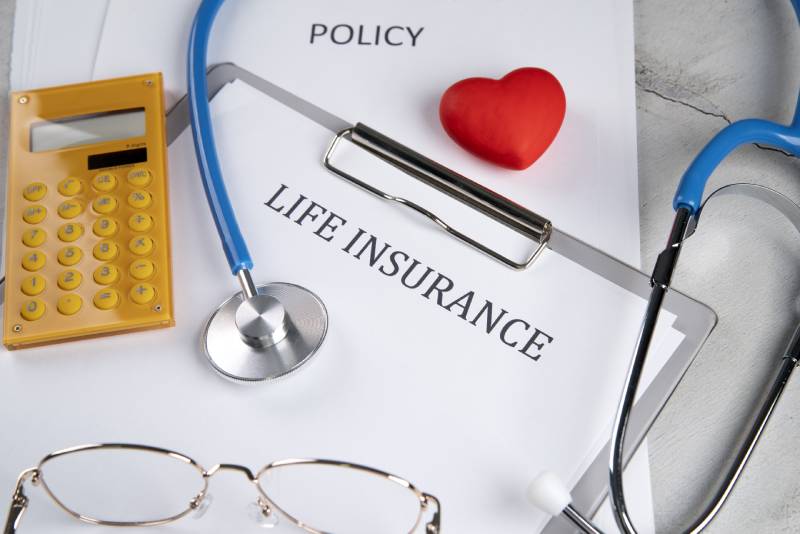 A life insurance policy, stethoscope, and calculator representing insurance options for individuals with diabetes.