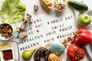 Healthy' and 'Unhealthy' written on paper, surrounded by foods, showing the link between poor diet and diabetes-related malnutrition.