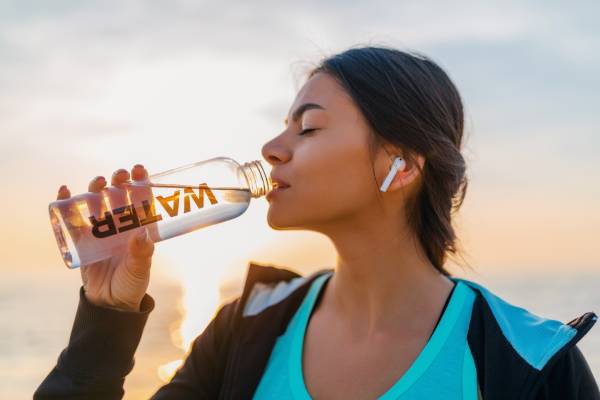 Young woman drinking water to emphasize hydration’s role in diabetes management during festive days.