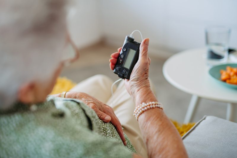 An elderly woman checking her insulin pump to control blood sugar levels for diabetes.