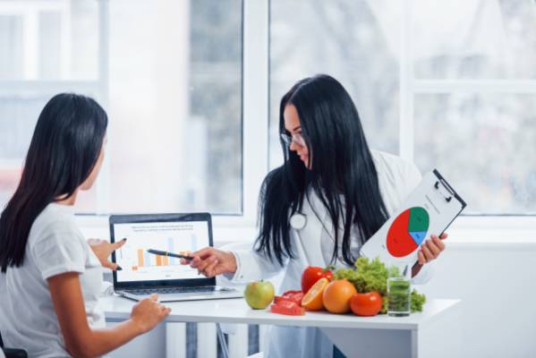 Doctor explaining a healthy diet plan with charts and graphs, showing how lifestyle changes can lower diabetes risk.