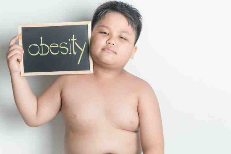 An overweight boy holding a slate labeled 'obesity,' indicating its association with type 2 diabetes.