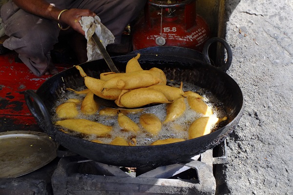 A person frying food outdoors, highlighting fat foods that should be avoided in a diabetic diet.