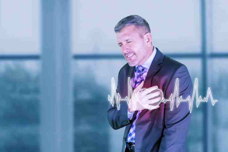 Man clutching his chest with a heartbeat graphic, indicating a symptom of hypoglycemia.