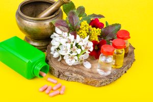 Herbal medicine with flowers, capsules, essential oils, and a brass mortar representing Siddha as part of an integrated diabetes treatment approach.