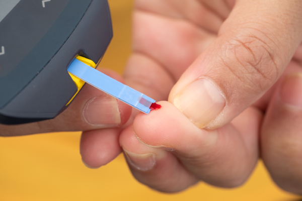 A blood sample touches the glucometer strip, triggering a reaction that displays the sugar level digitally.