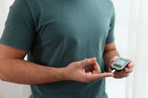 A man checking his blood sugar levels at home using a glucometer.