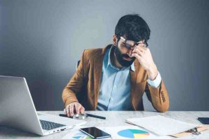 Diabetic man struggling to concentrate at work, illustrating hyperglycemia caused by high blood sugar levels.