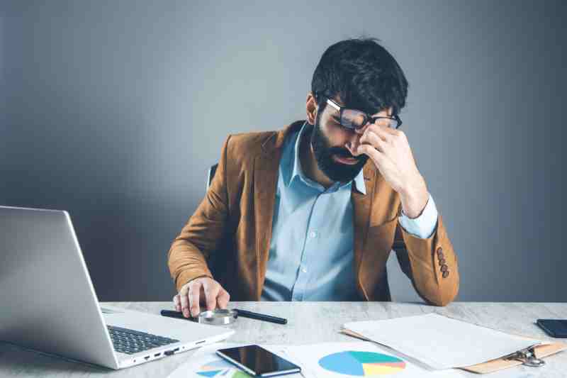 Diabetic man struggling to concentrate at work, illustrating hyperglycemia caused by high blood sugar levels.