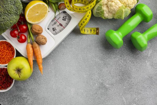 Fresh fruits, vegetables, dumbbells, and a scale symbolize weight loss for diabetes control.