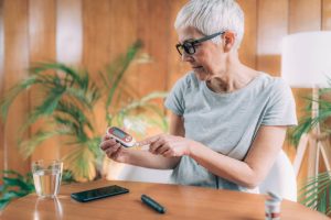 An older woman checking her glucose level reflects the increased risk of type 2 diabetes with age.
