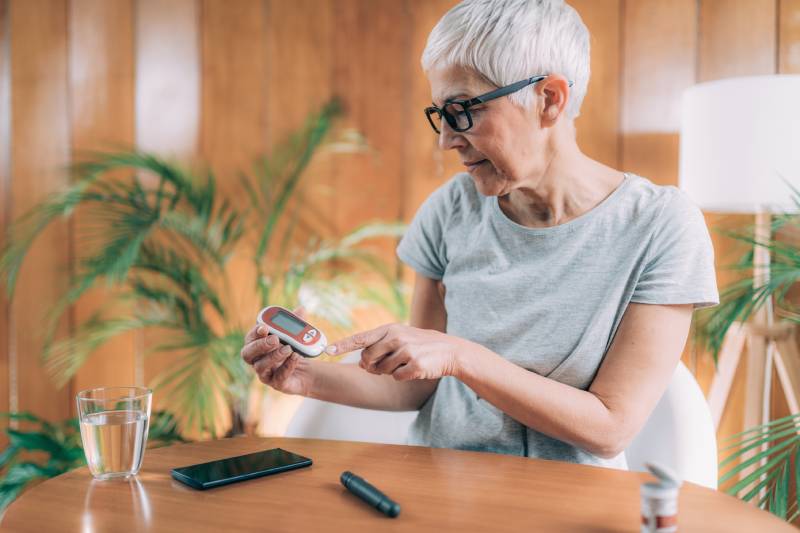 An older woman checking her glucose level reflects the increased risk of type 2 diabetes with age.