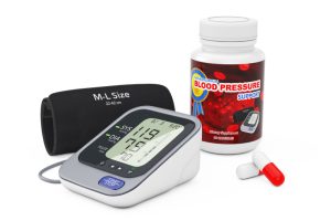 Digital blood pressure monitor and pills, highlighting the role of medication in managing hypertension.