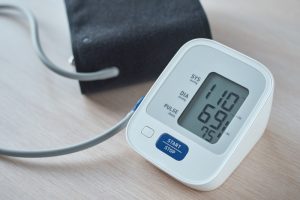 A digital monitor on a table is used to check systolic and diastolic pressure.