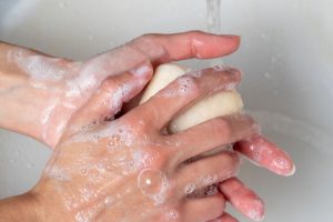 Person washing hands with soap, a habit that helps stop the spread of germs and prevent fever.