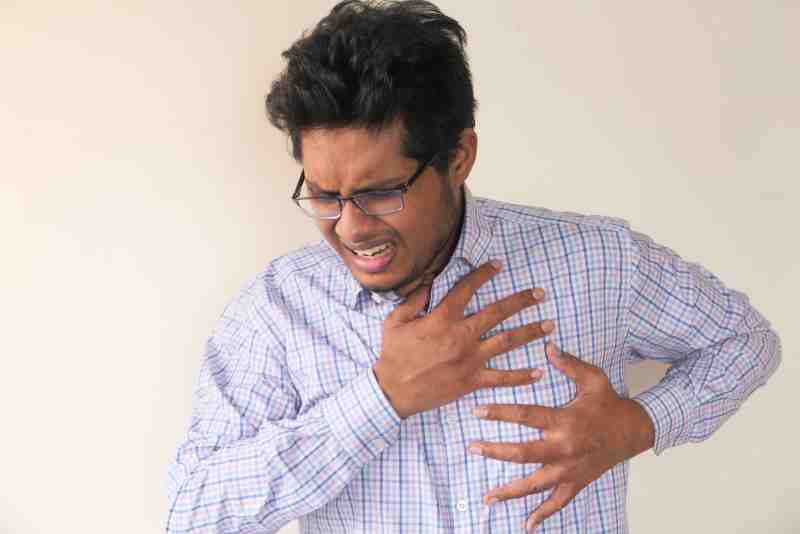 Man clutching his chest, showing symptoms that may indicate a silent heart attack.