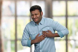 Young man clutching his chest in pain, indicating a possible heart attack.