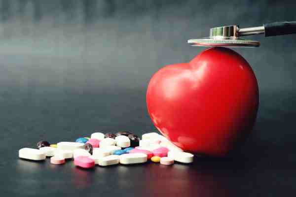 Stethoscope on a red heart with pills, highlighting the role of medications in heart attack treatment.