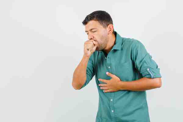 Man experiencing nausea with hand on chest and stomach, suggesting early heart attack symptoms.