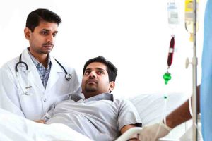 A doctor is standing beside a male patient in a hospital bed, offering support after a heart attack.