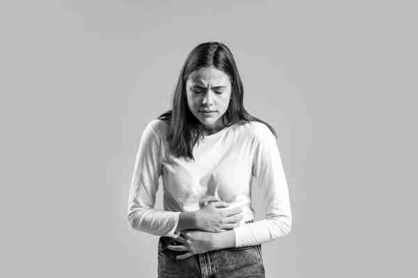 Woman holding her stomach in pain, showing atypical symptoms that may indicate a heart attack.