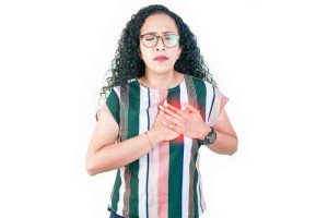 Woman clutching her chest, illustrating how heart attack symptoms can be subtle and easily overlooked.
