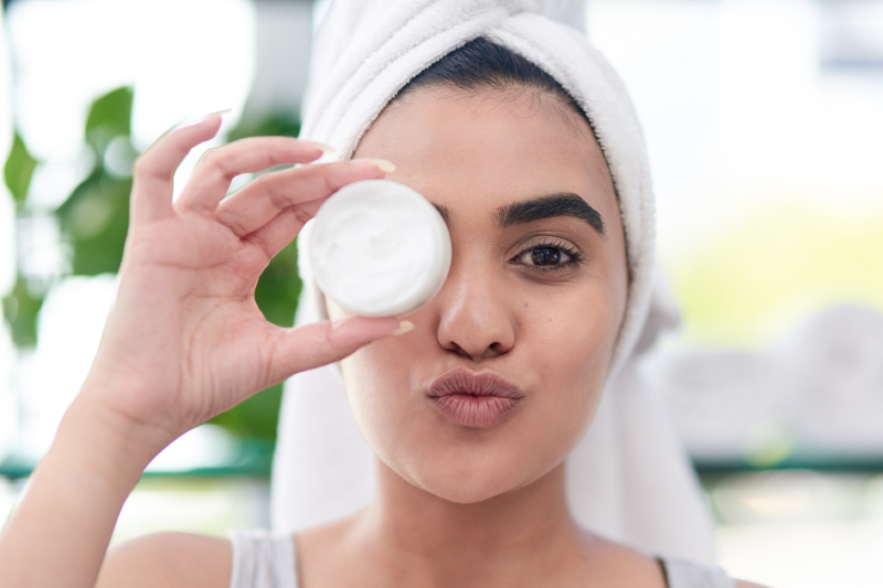 Woman poses with face cream after a bath, representing glowing skin care routines in winter.