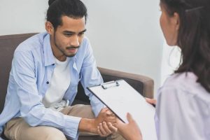 Psychologist and a young man in conversation, illustrating therapeutic counseling for depression.