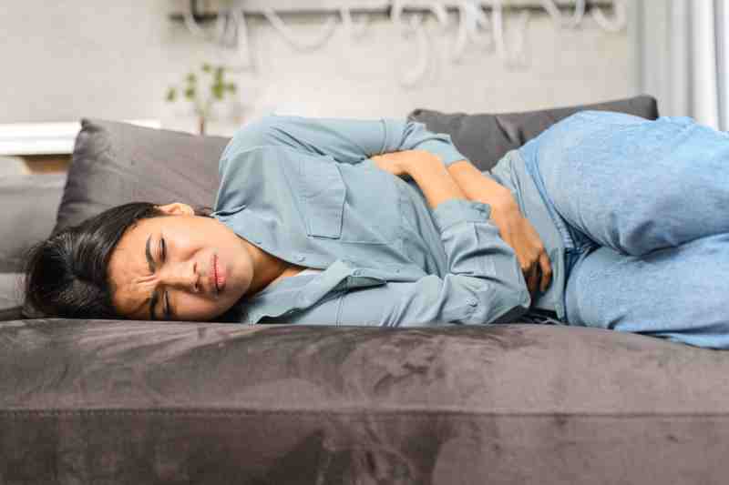 Woman experiencing severe stomach pain due to menstrual cramps, highlighting the impact of dysmenorrhea on daily life.