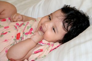 Baby lying on a bed and smiling, reflecting healthy emotional and developmental growth.
