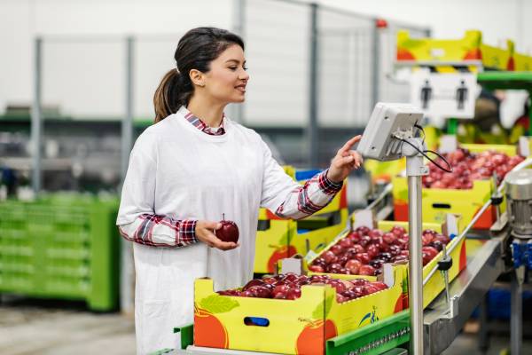 A woman holding an apple and using a touchscreen, highlighting the FIFO system.