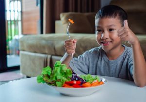 A boy enjoys a healthy salad, promoting growth, brain function, and lifelong health.