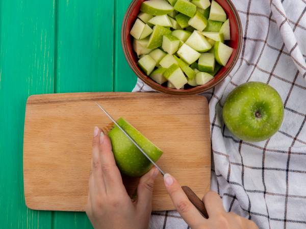 Hand cutting green mango into medium chunks, first step in homemade pickle making.