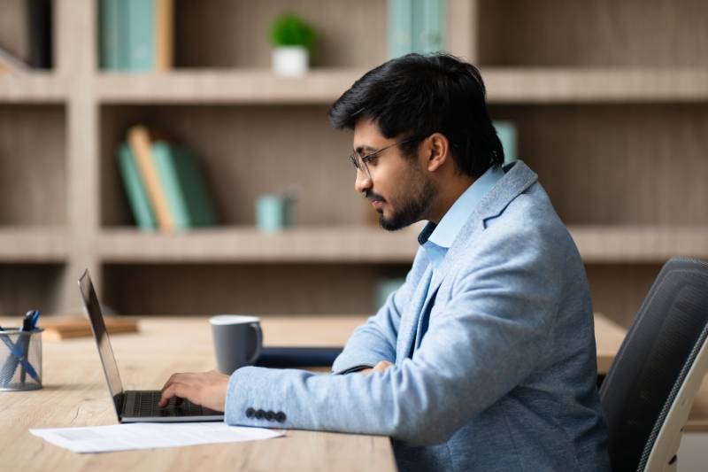 Man working on a laptop at proper distance and height, showing a comfortable work environment.