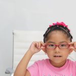 A young girl adjusting her glasses, suggesting common causes of eye problems in children.